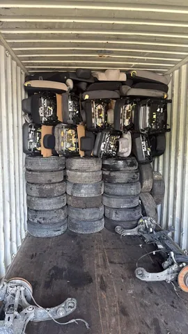 Seats and tires arranged inside a shipping container at Engine Corner Auto Parts LLC.